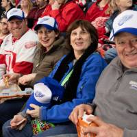 Four alumni smile for a photo at the Detroit Red Wings GVSU Night